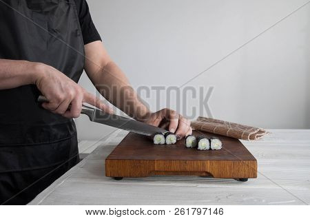 Process of making maki sushi. Cook chef hands preparing rolls with cheese, avocado and sesame seeds 