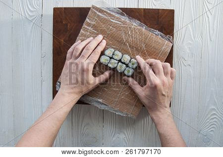 Process of making maki sushi. Cook chef hands preparing rolls with cheese, avocado and sesame seeds