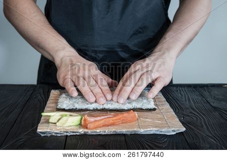 Process Of Making Maki Sushi. Cook Chef Hands Preparing Rolls With Cheese, Avocado And Sesame Seeds 