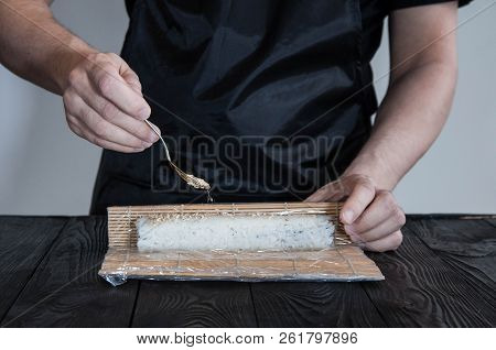 Process Of Making Maki Sushi. Cook Chef Hands Preparing Rolls With Cheese, Avocado And Sesame Seeds 