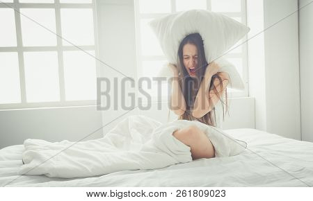 Young Caucasian Woman Covering Her Head And Ears With Pillows.