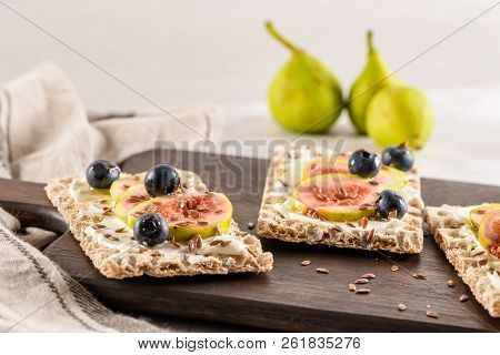 Canape Or Crostini With Multigrain  Crispread With Cream Cheese And Fresh Fig Slices On A Wooden Boa