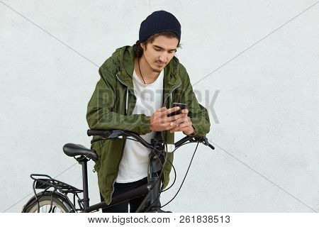 Stylish Youngster In Black Hat And Jacket With Hood, Has Active Lifestyle, Covers Long Distances Wit