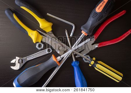 A Black Wooden Background With Various Hardware Tools: Wrench, Hexa Key, Nut, Cutting Pliers, Pliers
