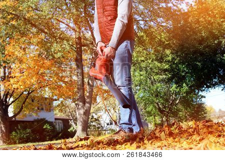 Man Working With  Leaf Blower: The Leaves Are Being Swirled Up And Down On A Sunny Day