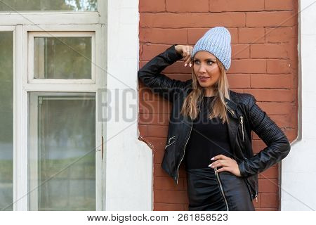 Young Attractive Lady In Blue Knitting Hat Stay Under  Brick House, Look Away. Smiling Beautiful Hip