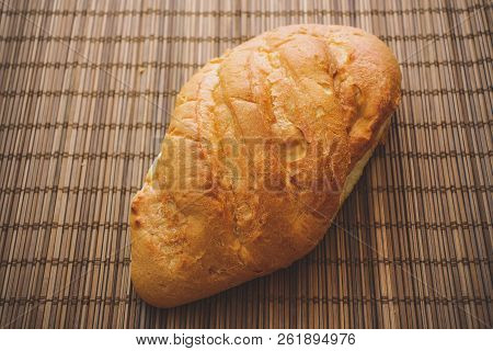 Bun On A Straw Brown Litter.
Freshly Baked Loaf Of Bread On A Straw Mat.