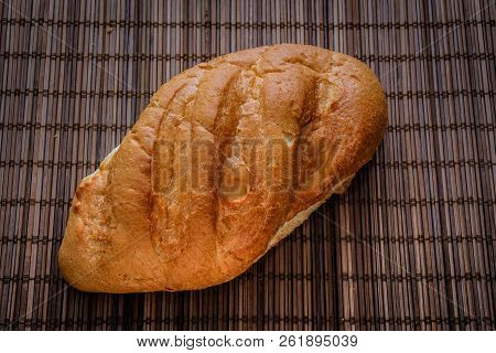 Bun On A Straw Brown Litter.
Freshly Baked Loaf Of Bread On A Straw Mat.