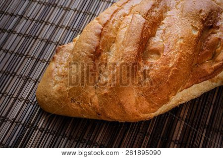 Bun On A Straw Brown Litter.
Freshly Baked Loaf Of Bread On A Straw Mat.