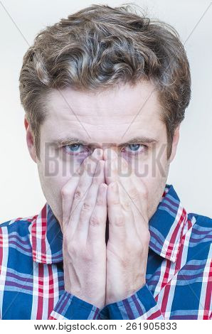 Portrait Of Young Tranquil Concentrated Thinking Man Covering Face With Palms On White Background.