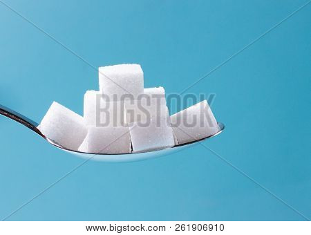 Sugar Cubes In Spoon On Blue Background