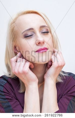 Relaxation And Meditation Techniques. Young Blonde Closed Eyes Woman Holding Earlobes With Fingers.