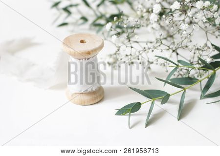 Feminine Floral Scene. Close-up Of Spool Of Silk Ribbon, Eucalyptus Parvifolia Leaves And Babys Brea