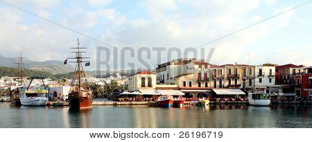 Uma vista panorâmica sobre o porto veneziano em Rethymnon, Creta, com a cidade e montanhas em 
