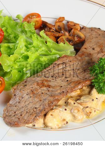 Visualizzazione verticale di un pasto di una Scaloppina di vitello su letto di funghi in salsa di panna e aglio, servito