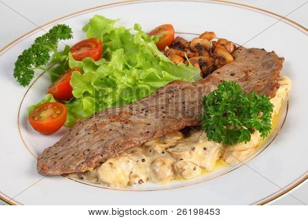 Un pasto di una Scaloppina di vitello su letto di funghi in salsa di panna e aglio, servita con lattuga, ch