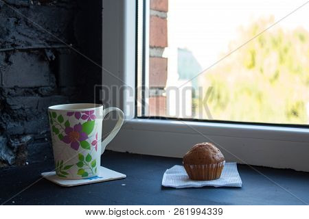A Cup With Tea And Cupcake Near The Window