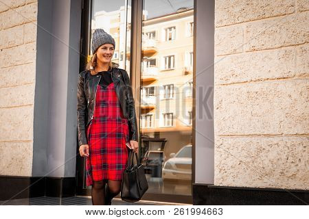 Young Female Student In Warm Autumn Clothes Coming Out Of The House With A Backpack With Books  Arou