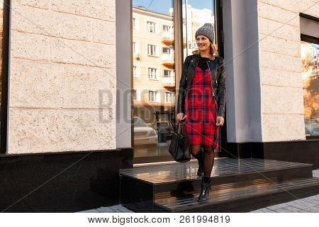 Young Female Student In Warm Autumn Clothes Coming Out Of The House With A Backpack With Books  Arou