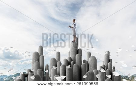 Young Female Doctor With Folder In Hands Satnding On Stone Column
