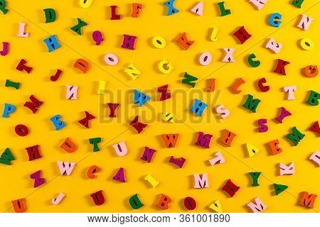 Multicolored Alphabet Background. Colorful Letters Of The English Alphabet Are Scattered On Yellow B