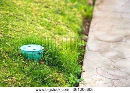 Closeup Of Green Plastic Pipe With Cover On Green Grass Lawn.