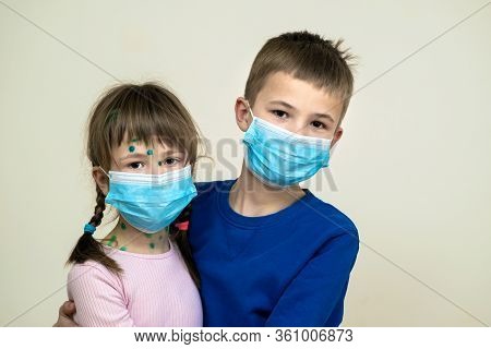 Boy And Girl Wearing Blue Protective Medical Mask Ill With Chickenpox, Measles Or Rubella Virus With