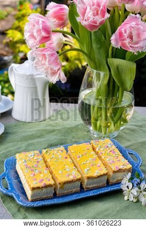 Four Tompouce Cakes With Whipped Cream And Yellow Icing Served In Sunny Spring Garden