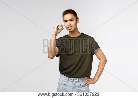 Portrait Of Frustrated And Concerned Asian Man Grimacing, Cringe From Something Strange And Disgusti