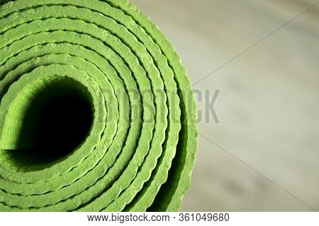 The Yoga Mat Of Green Color Lies On The Floor. Healthy Lifestyle. Light Background In Blur.