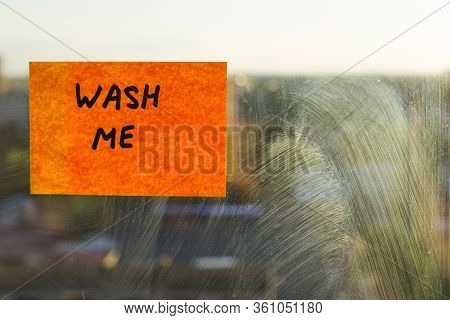 Wash Me, Inscription On Pasted Note, Dirty Window In The Mud Stains. A Bright Orange Sticker. Backgr