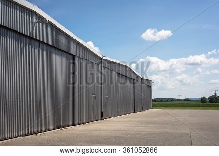 Metal Structure Hangar From A Private Airport In Germany. Hangar Exterior View On A Beautiful Summer