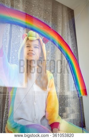 Girl In Kigurumi Unicorn Draws The Rainbow On The Window. Stay Home. Flashmob Chasetherainbow.
