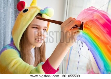 Brush. Teen Girl In Kigurumi Unicorn Draws The Rainbow On The Window. Flashmob Chasetherainbow. Stay