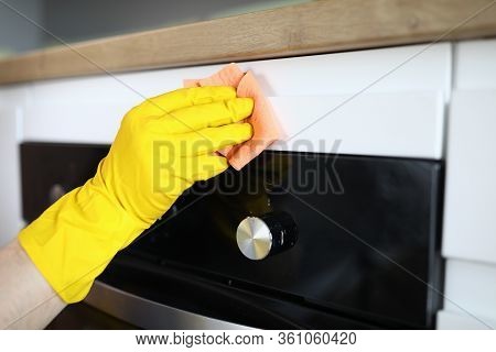Close-up Of Persons Hand In Yellow Protective Gloves Cleaning Kitchen Appliance With Pink Rag. Moder