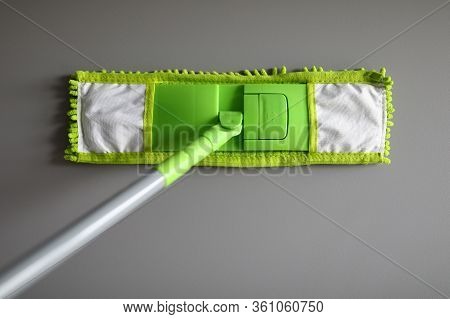 Top View Of Green Mop With Handle For Floor Cleaning. Macro Shot Of Fluffy Rag. Equipment Of Profess