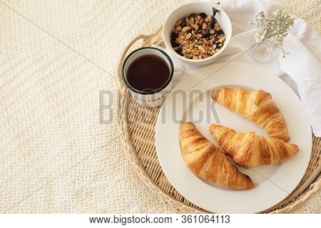Close Up Of Tray With Coffee Cup, Croissants, Muesli And White Flowers On Knitted Blanket At Cozy Sc