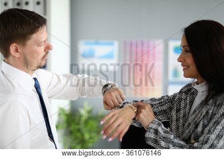 Portrait Of Business Co-workers Smiling And Reconcile Time On Wristwatch. Brunette Young Woman And M