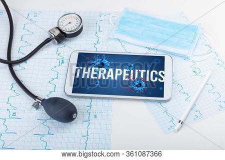 Tablet pc and doctor tools on white surface with THERAPEUTICS inscription, pandemic concept