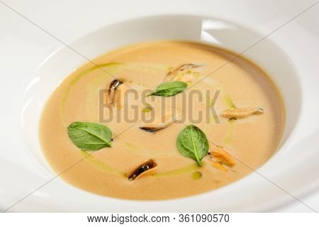 Chilean mussels soup in white bowl. Served main course close up. Seafood cream soup with roasted bread slice. Restaurant food portion, main course with toast. Dinner, gourmet meal in plate