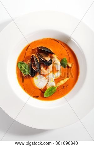 Bouillabaisse in white bowl. Served main course close up. French seafood, soup with fish and mussels. Restaurant food portion, main course. France cuisine. Dinner, gourmet meal in plate