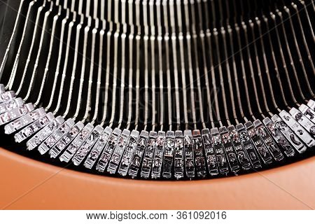 A Close-up Or A Macro Shot Of The Typebars Of A Retro-style Manual Typewriter Encased In A Hinged Re