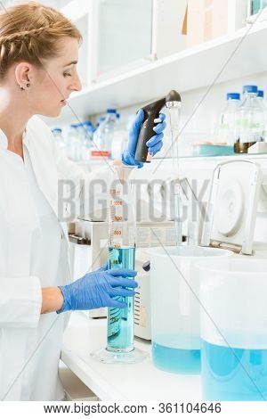 Young female doctor testing chemicals wearing labcoat and hand gloves in a laboratory