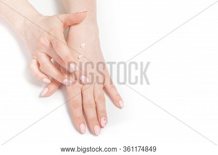 The Women Distributes Moisturizing Cream On Her Hands. Hands On A White Background With A Jar Of Whi