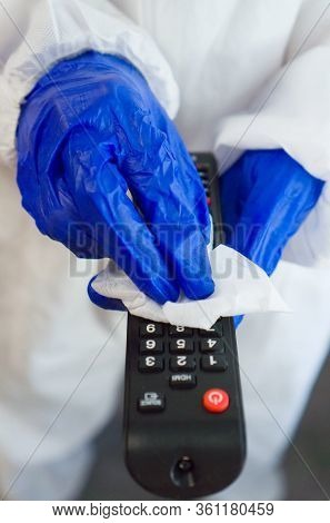 Hand In Protective Glove With Napkin Cleaning Remote Control. Covid-19 Disinfection Concept.