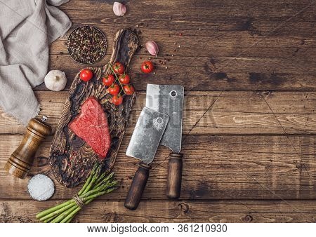 Slice Of Raw Beef Sirlion Steak On Wooden Chopping Board With Tomatoes,garlic And Asparagus Tips And