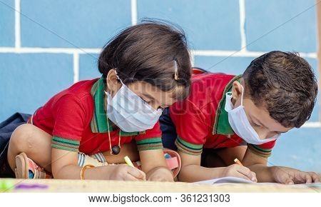 Kids Busy In Writing With Medical Face Mask Wearing Due To Covid-19 Or Coronavirus Outbreak Or Pande