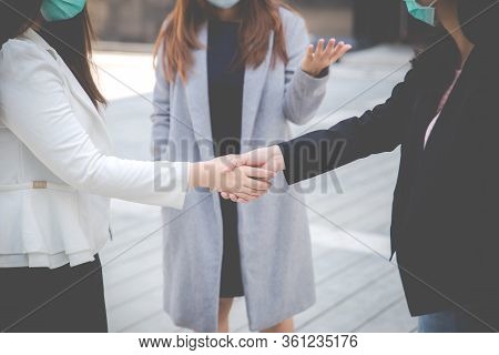 Businesswomen Shaking Hands With People In The Background. Two Confident Businesswomen Shaking Hands