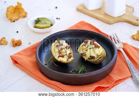 Twice Baked Potatoes With Cheese And Chanterelle Mushrooms On A Brown Clay Plate On A Light Concrete
