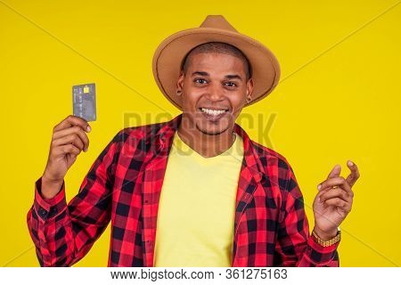 Afro Brazilian Man With Credit Card In Stusio On Yellow Background.farmer Taking A Loan In A Bank Fo